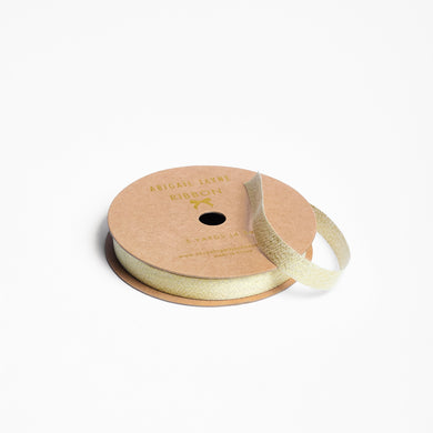 Spool of metallic gold ribbon on a white background