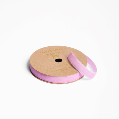 Spool of mauve pink  velvet ribbon on a white background